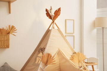 Stylish wigwam with dry leaves in child's room, closeup. Space for text © New Africa
