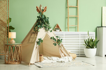 Cute wigwam with leaves and blanket in stylish child's room © New Africa