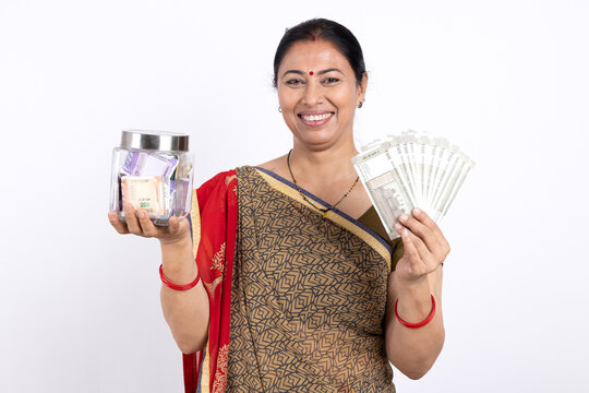 Indian happy rural woman holding indian rupees 
and money jar on white background