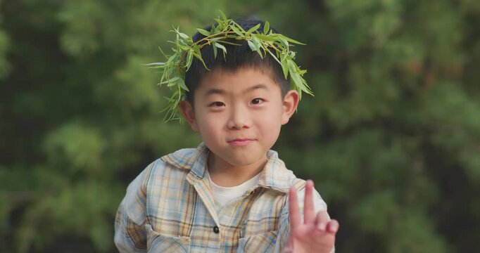 A Chinese mother and child play outdoors wearing willow leaf-woven clothes.