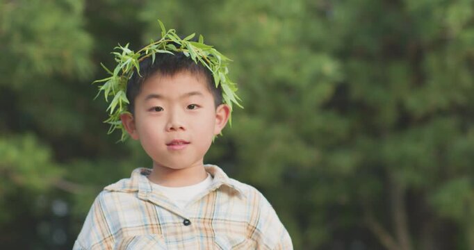 A Chinese mother and child play outdoors wearing willow leaf-woven clothes.