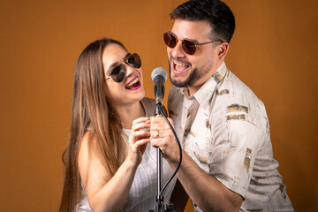 Fototapeta premium Pareja de hombre y mujer divirtiendose cantando juntos con un micrófono