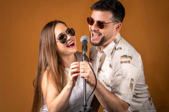 Pareja de hombre y mujer divirtiendose cantando juntos con un micr&oacute;fono