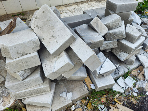 Pile of broken AAC blocks at construction site, showing cracked lightweight bricks with rough texture and dust, representing material waste, damage, and ongoing building or renovation process