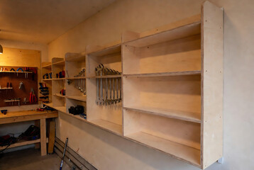 Obraz premium A DIY workbench with shelves and tool storage is being constructed in a garage.