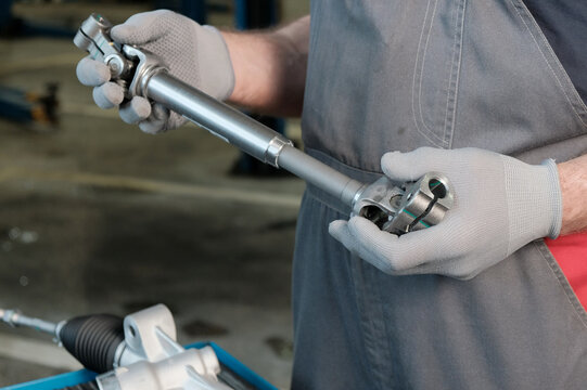 Installing a new steering rack.An auto mechanic prepares the steering rack for installation. Inspection of the new steering driveshaft, checking the compatibility of the control unit parts.