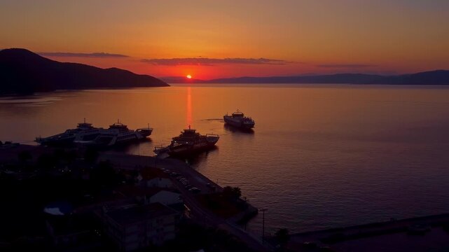 Ferry docking at Thasos port during sunset, long aerial shot with golden sea reflection