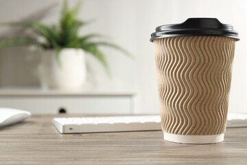 Coffee in takeaway paper cup at workplace in office , closeup. Space for text