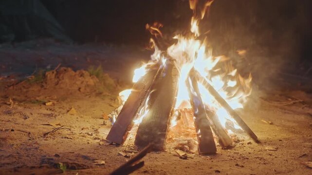 Campers share laughs around glowing bonfire. Lively night with friends gathered around warm campfire glow. Cheerful group of campers exchange tales and roast marshmallows under starry skies
