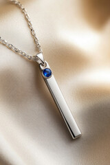 Fototapeta premium A close-up of a silver necklace featuring a blue stone. vertical frame