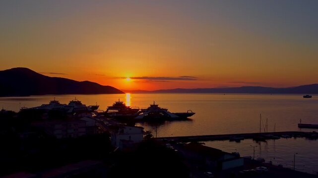 Harbor in Thasos, Greece, at sunset with a small boat moving on a calm sea, aerial view