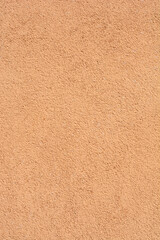 Fototapeta premium Rough texture of a pastel apricot stucco wall with a uniform sandy finish suitable for architectural or construction backgrounds. 