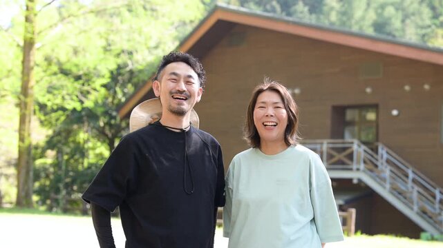 笑顔の夫婦が別荘やキャンプやアウトドア、地方移住などのイメージでカメラ目線で笑顔の動画　スローモーション