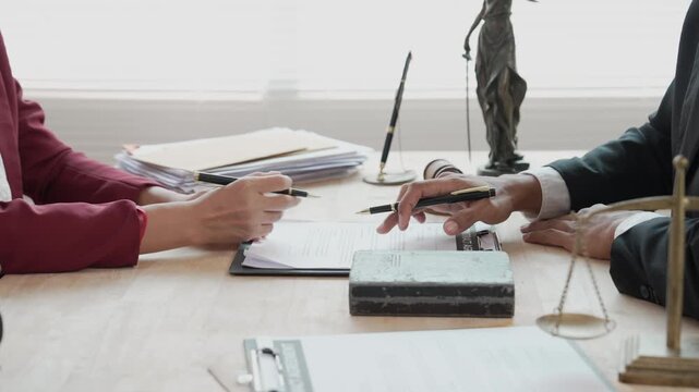 The concepts of law and justice are explained and discussed by lawyers regarding contracts and legal documents, providing advice to clients in their office.