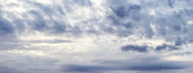 Fototapeta premium Overcast grey-blue sky with dark clouds of various shapes, panoramic view, natural lighting
