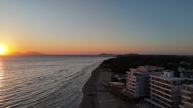 Sunset aerial view of coastline with buildings and sea horizon