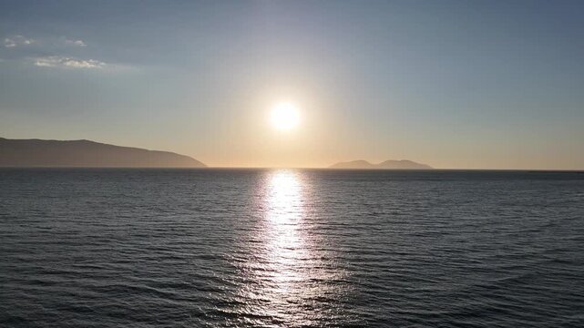 Aerial drone view of coastal sea at sunset with warm light and scenic horizon.