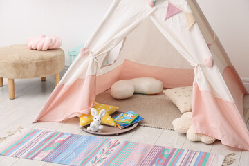 Cute wigwam with pillows, books and toys in stylish child's room © New Africa