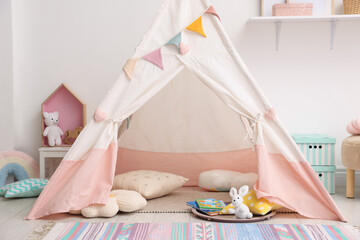 Cute wigwam with pillows, books and toys in stylish child's room © New Africa