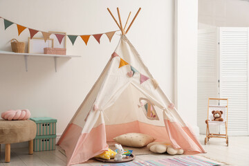 Cute wigwam with pillows, books and toys in stylish child's room © New Africa