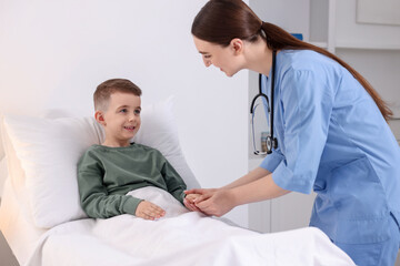 Fototapeta premium Doctor examining little child on bed in hospital