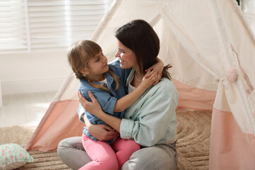 Mother and her daughter near toy wigwam at home © New Africa