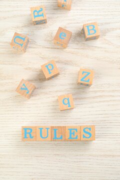 Word Rules made of cubes with letters on light wooden table, flat lay