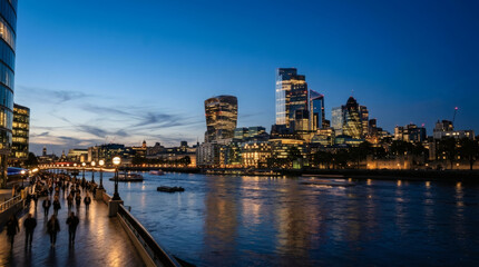 Fototapeta premium Photograph of a city skyline at dusk with modern skyscrapers illuminated against a blue sky, reflected in a calm river.