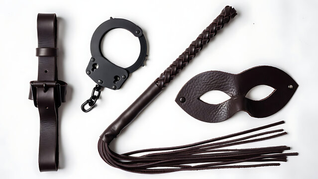Brown leather adult lifestyle accessories set with belt handcuffs braided flogger and masquerade mask on white background