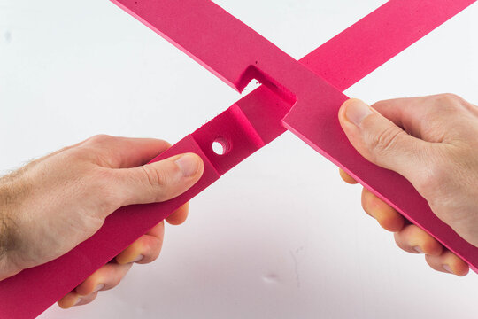 A detailed shot showing hands interlocking pink EVA foam base pieces using a bright green plastic connector