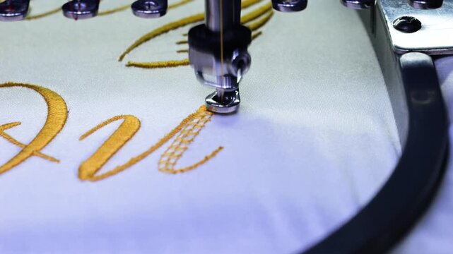 Machine embroidery of text with gold thread on a white satin robe. Preparation for the wedding day. Elegant bridal lingerie. Close-up.
