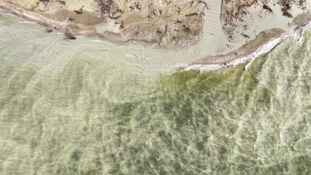An aerial view of the natural formations created by waves and shallow waters along the lake shore. A serene drone shot capturing the abstract patterns formed by sand, water, and wind.