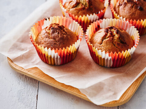 The image shows fresh muffins placed on a wooden tray with colorful liners. Ideal for restaurant menus, food blogs, and advertising promotions