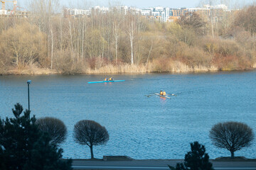 Rowers training on a wide city river with urban skyline © BY-_-BY