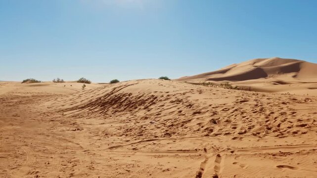 First person view walking on the orange sand of the erg chebbi desert in morocco under a clear blue sky on a sunny day
