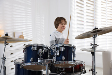 Obraz premium Little boy with drumsticks learning how to play drums indoors