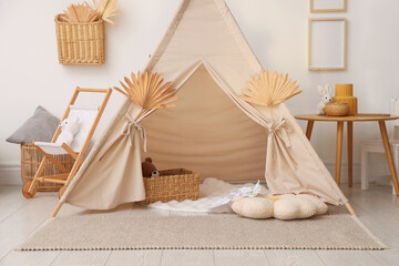 Stylish wigwam with dry leaves in child's room © New Africa