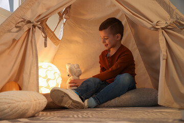 Little boy playing with toys in wigwam at home © New Africa