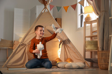 Little boy playing with toys near wigwam at home © New Africa