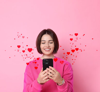 Happy woman reading love message against pink background. Hearts flying out of mobile phone