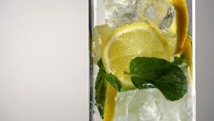 Fresh sparkling lemonade with lemon slices mint leaves and ice cubes in glass. Concepts of summer...