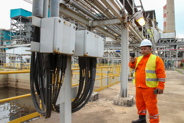 Fototapeta premium Industrial engineer in Orange Safety Vest Inspecting Power Plant Equipment
