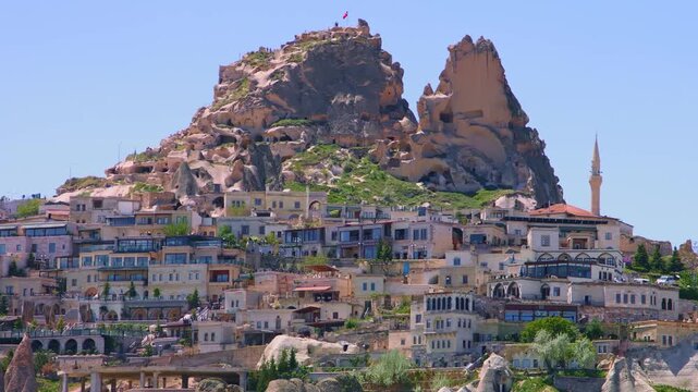 A daytime, eye-level shot captures the majestic Uchisar Castle, the highest point in Cappadocia, Turkey, towering above the surrounding town built into the unique volcanic rock formations, known as "f