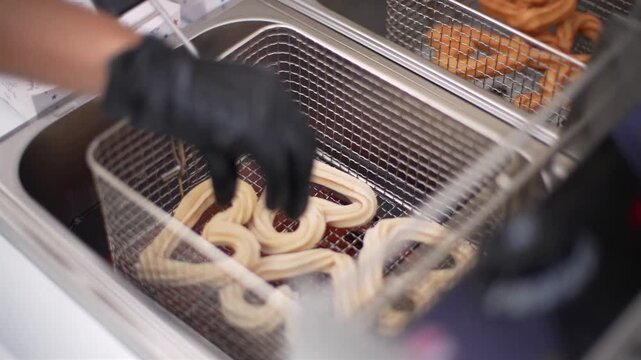 Person operating a fryer making heart-shaped churros