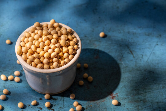 Soybeans in a white ceramic bowl on blue surface 