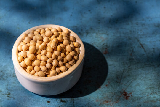 Soybeans in a white ceramic bowl on blue surface 