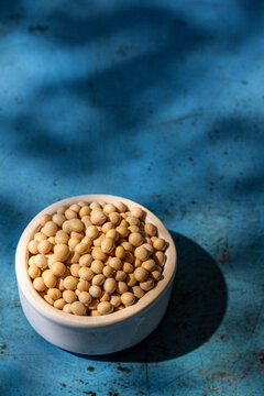 Soybeans in a white ceramic bowl on blue surface 