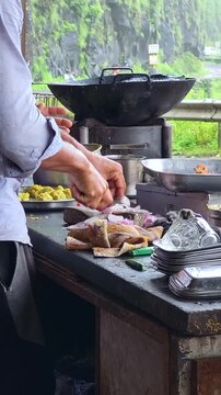 Rainy season street stall scene as fresh onions are sliced for hot vada pav. Steam rises, raindrops fall outside, and spicy aromas fill the air in a cinematic close-up food moment.