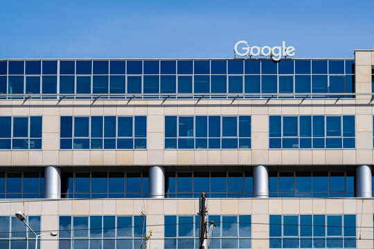 Modern Google office building with logo on rooftop, corporate headquarters facade with glass windows, technology company branch architecture, business district exterior, professional workplace environ