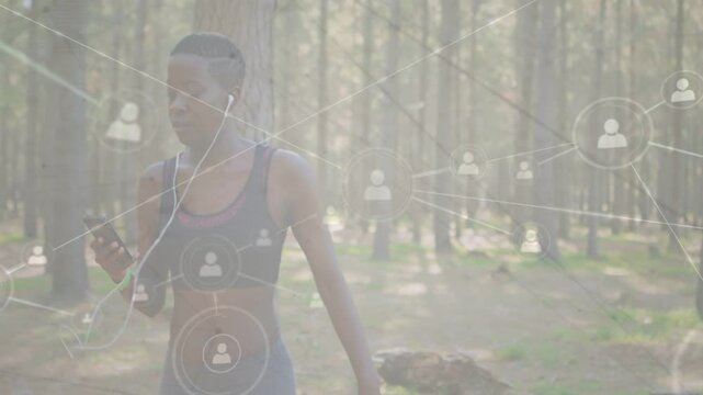 Woman entering frame tapping smartphone while walking forest path, activating fitness UI overlay